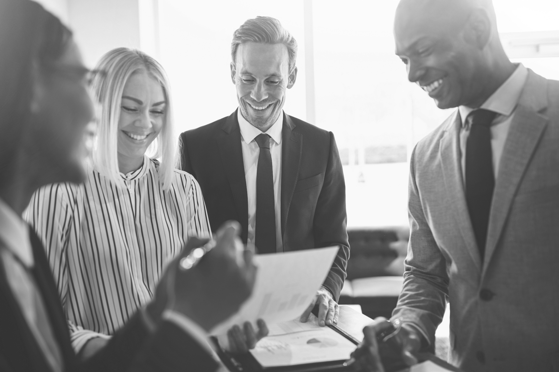 Diverse businesspeople smiling while meeting together around an office table